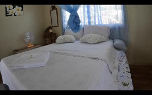 uma grande cama branca com uma cabeceira e almofadas azuis em welcome to putuo ecolodge hidden germ of Solomon 