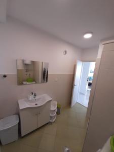 een witte badkamer met een wastafel en een spiegel bij Pere Apartment in Omiš