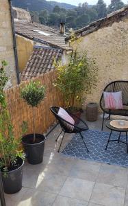 a patio with two chairs and a table and potted plants at Proche d'Uzès la Terrasse du soleil levant in Collias