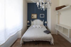 een blauwe slaapkamer met een bed en een kroonluchter bij Dogana d'Acqua Rooms & Art in Livorno