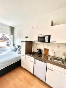 una cocina con armarios blancos y una cama en una habitación en BUDGET City Appartement Küche,Bad, Parken im Zentrum von Ravensburg en Ravensburg