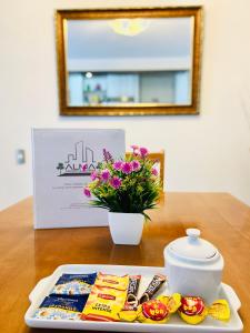 a table with a plate of food and a vase with flowers at Apartamentos Alma Surire in Arica