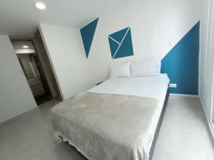 Un dormitorio con una cama con una pared de acento azul en Apartamentos en Club Residencial con Piscina, en Ibagué