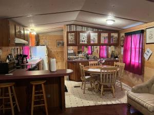 a kitchen with a table and a kitchen with pink curtains at Twin Oaks in Bryson City