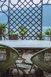 two green chairs sitting at a table in front of the ocean at Ca Meison in Cannobio