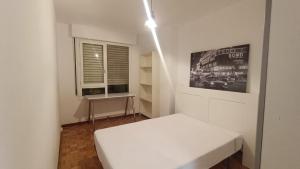 Cette chambre blanche dispose d'un lit et d'une fenêtre. dans l'établissement Apartamento centro Vitoria, à Vitoria-Gasteiz