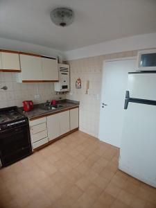 una cucina con armadietti bianchi e frigorifero nero di 2 amb Maral 48 Mar del Plata a Mar del Plata