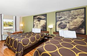duas camas num quarto de hotel com pinturas na parede em Super 8 by Wyndham Kingsport em Kingsport
