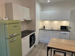 eine Küche mit weißen Schränken und einem grünen Kühlschrank in der Unterkunft La Résidence Alpha Viroflay 002 - 1 chambre - 4 pers in Viroflay