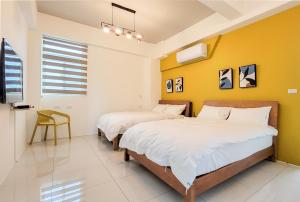 2 Betten in einem Zimmer mit gelben Wänden in der Unterkunft Mo Guesthouse in Shangwu