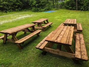tres mesas de picnic de madera sentadas en el césped en Chalet le Rassembleur, en Racine