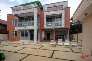 un edificio con sillas en un patio frente a él en Classy Studio Apartment, East Airport, en Accra