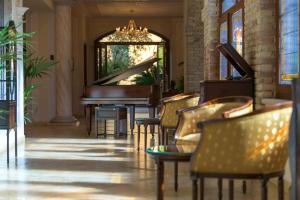 vestíbulo con piano, sillas y lámpara de araña en Hotel Antico Monastero, en Toscolano Maderno