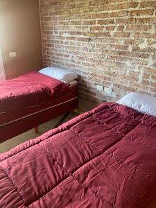 2 camas en una habitación con una pared de ladrillo en San Polo departamentos en La Consulta
