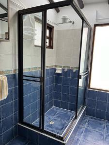 - une douche carrelée de bleu avec une porte en verre dans l'établissement Zingara de la Montaña: Hermosa Casa en Zipaquira, à Zipaquirá