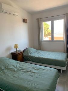 1 dormitorio con 2 camas verdes y ventana en Jolie maison individuelle dans l’extrême sud, en Monacia-d'Aullène