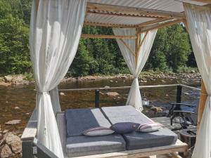 uma cama na parte de trás de um barco ao lado de um rio em Domaine de la rivière Montmorency, chalet luxueux em Sainte Brigitte de Laval