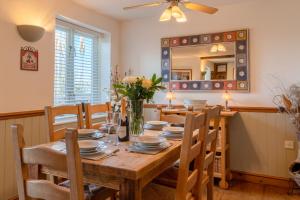 a dining room with a table with chairs and a mirror at Moorhens in Somerford Keynes