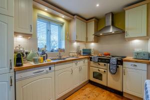 a kitchen with white cabinets and a stove top oven at Moorhens in Somerford Keynes +18 photos
