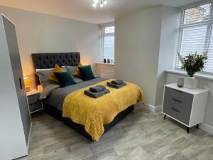 a bedroom with a large bed with a yellow blanket at Spot Chambers in Derby