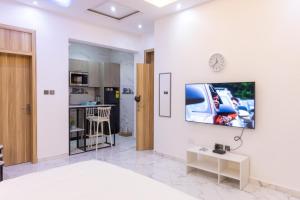 Una sala de estar con una cama y un televisor en una pared. en Cozy Studio Apartment, East Airport, en Accra