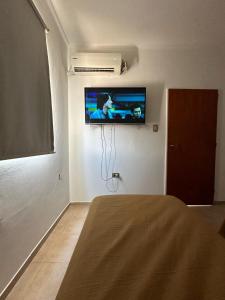 Cette chambre dispose d'une télévision murale et d'un lit. dans l'établissement Departamentos Crisol, à San Fernando del Valle de Catamarca