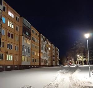 a snow covered street in front of a building at Quiet apartment near park SELF CHECK IN in Šiauliai