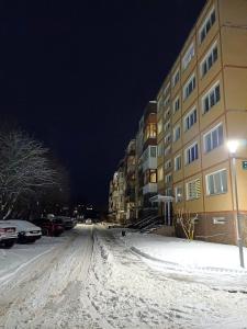una strada innevata di notte con un edificio di Quiet apartment near park SELF CHECK IN a Šiauliai