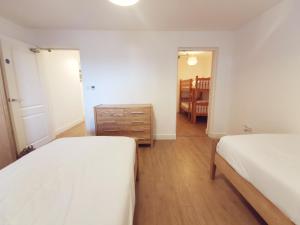 a bedroom with two beds and a dresser in it at 24 CLIFF APARTMENT-3 BED-GROUND FLOOR-SEA VIEWS in Trearddur