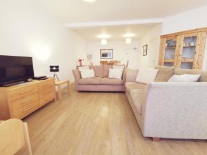 a living room with a couch and a tv at 24 CLIFF APARTMENT-3 BED-GROUND FLOOR-SEA VIEWS in Trearddur
