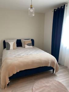 a bedroom with a large bed with blue curtains at Villa by Nesma in Châtellerault
