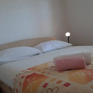 a bed with white pillows and a pink object on it at APARTMANI NEDA in Živogošće