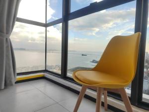 una silla amarilla sentada frente a una gran ventana en Seaview Infinity Pool/ 40th/ 10pax/ 3Rooms 2Carpark, en Jelutong