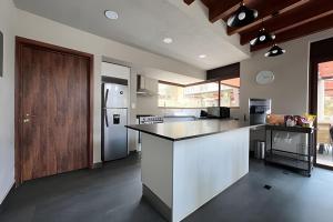a large kitchen with a counter and a refrigerator at Casa con alberca y jacuzzi in Avándaro