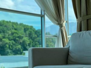 un canapé installé devant une grande fenêtre dans l'établissement Comfy 2 Bedder Retreat Homestay near Taiping Lake Garden with Netflix, à Taiping