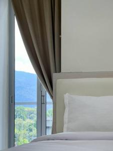 ein Schlafzimmer mit einem Bett und einem großen Fenster in der Unterkunft Comfy 2 Bedder Retreat Homestay near Taiping Lake Garden with Netflix in Taiping
