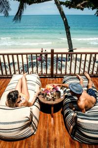 two people laying on chairs on a deck with the beach at Sand in My Shoes Beach Loft in Thong Nai Pan Noi