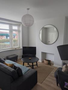 a living room with a couch and a mirror at Modern 3 bedroom home, close to City Centre and Peak District in Heeley