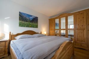 1 dormitorio con 1 cama grande con marco de madera en Ferienwohnungen Alpentraum - TraumZeit, en Oberstdorf
