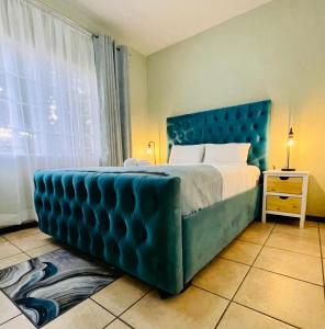 a bedroom with a large bed with a blue headboard at Tafre Hospitality @ Stratford, Menlyn in Pretoria