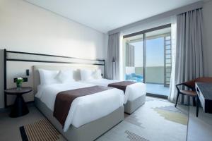 a hotel room with two beds and a large window at Fraser Suites Al Liwan in Manama