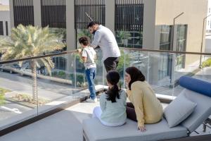 Fraser Suites Al Liwan في المنامة: مجموعة من الناس جالسين على شرفة ينظرون إلى رجل