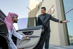 un hombre abriendo la puerta de un coche con un hombre parado afuera en Fraser Suites Al Liwan en Manama