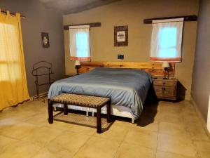 a bedroom with a bed and a bench and two windows at Casas de Campo El Rincón in San Antonio