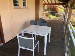 einen weißen Tisch und Stühle auf einer Veranda in der Unterkunft Appartement Emeraude et studio Azur in Gourbeyre