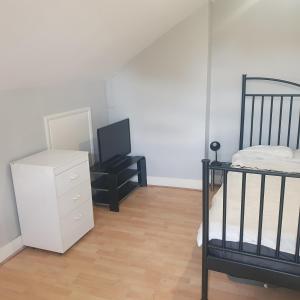 a bedroom with a bed and a dresser and a television at Flat with excellent transport links to central London. in Elmers End