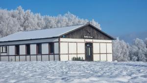 un edificio blanco y marrón con nieve en el suelo en Siedlisko na łące, en Dąbrówno