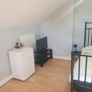 a bedroom with a white dresser and a television at Flat with excellent transport links to central London. in Elmers End