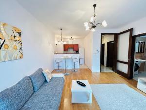 ein Wohnzimmer mit einem blauen Sofa und einer Küche in der Unterkunft BP Kazinczy Centrum Prime Suites in Budapest