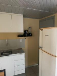 a kitchen with white cabinets and a refrigerator at Apto 1 ótimo local próximo shopping in Campo Grande